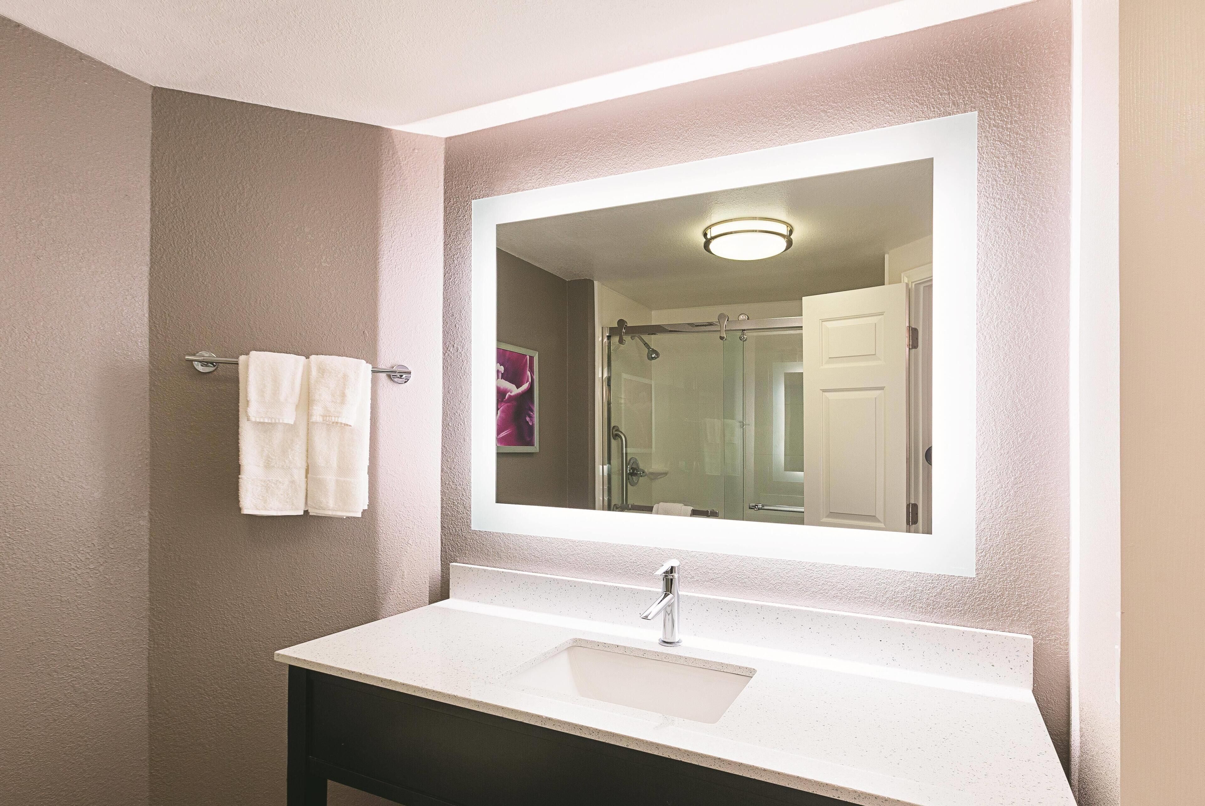 Un baño con un lavabo blanco, un espejo grande y un perchero para toallas.