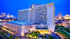 Ein Sheraton Hotel mit mehreren Etagen, einem Parkplatz und einer gut beleuchteten Fassade.