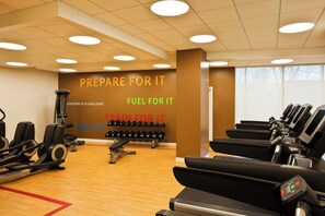 Ein Fitnessstudio mit Laufbändern, Kraftgeräten und Kurzhanteln.