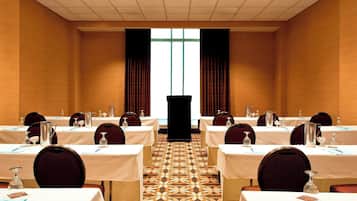A conference room with tables set for a meeting, a podium at the front, and a patterned carpet.