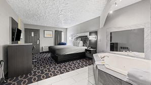 Une chambre d’hôtel moderne dotée d’un grand lit, d’une salle de bain séparée avec baignoire, d’un bureau et d’un téléviseur à écran plat.