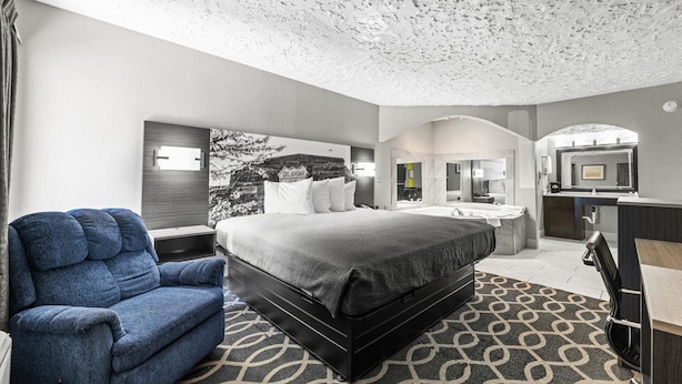 Une chambre d’hôtel dotée d’un grand lit, d’un coin salon, d’une salle de bain avec un miroir et d’une télévision.