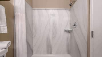 Una ducha con pared de mármol blanco, un cabezal de ducha y un panel de control.