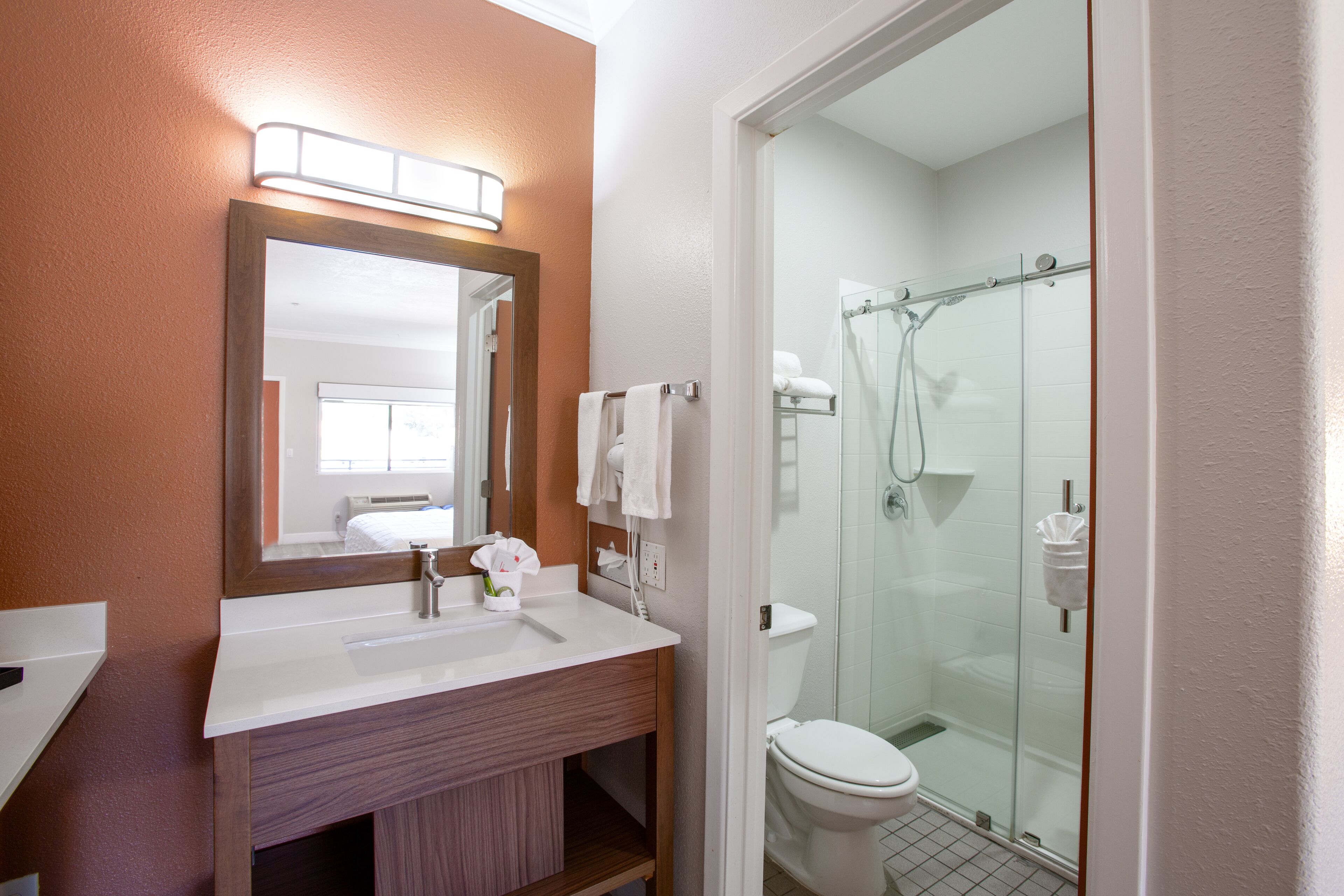 A bathroom with a sink, mirror, and glass shower enclosure.