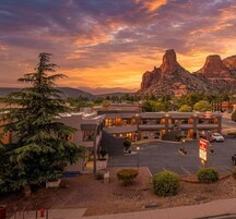 Un hotel con aparcamiento, una señal y una montaña al fondo.