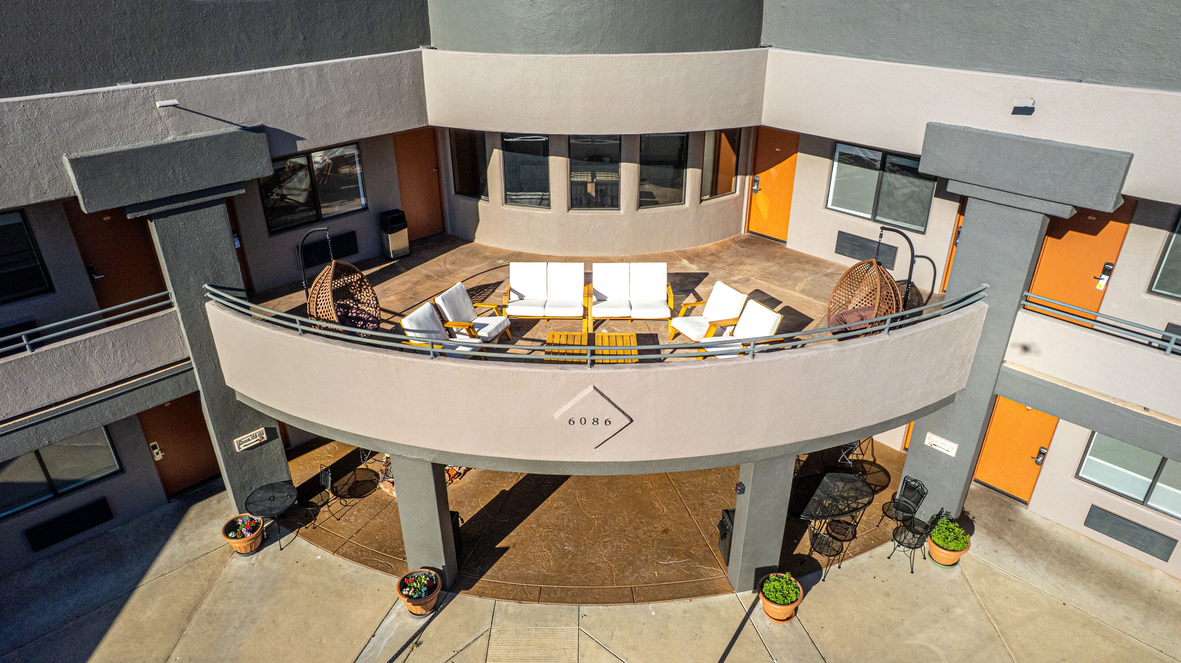 A circular outdoor seating area with multiple chairs and tables, surrounded by potted plants.