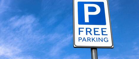 A parking sign with a blue 'P' and the words 'FREE PARKING' against a clear blue sky.