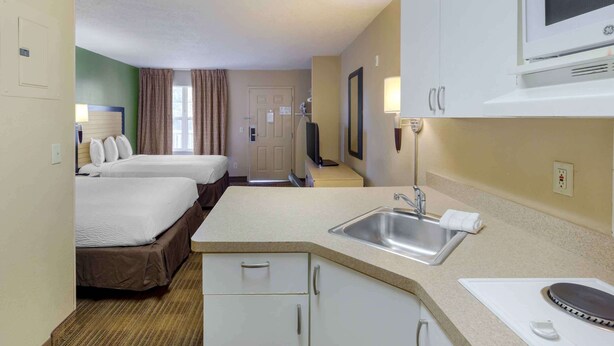 A hotel room with two beds, a kitchenette, a microwave, and a TV. - Extended Stay America Select Suites Fayetteville Owen Dr (Fayetteville)