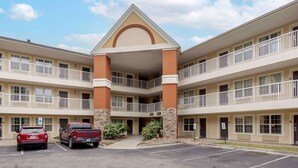 A multi-story hotel with a central atrium, balconies, and a parking lot with two vehicles. - Extended Stay America Select Suites Fayetteville Owen Dr (Fayetteville)