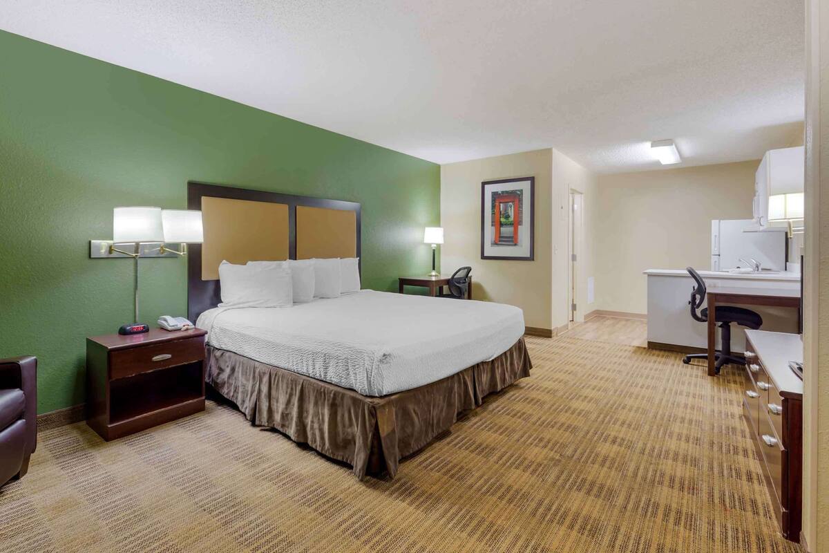Una habitación de hotel con una cama grande, mesitas de noche, un escritorio y una silla.