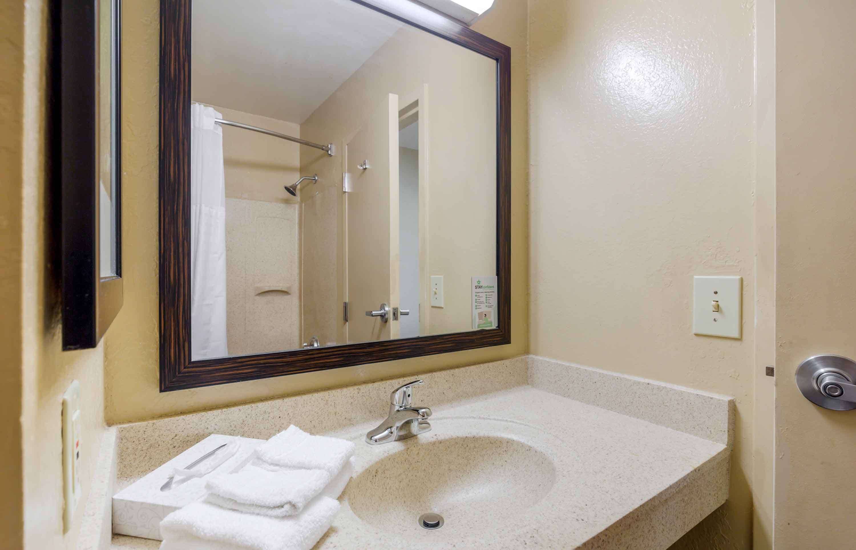 A bathroom with a sink, mirror, and towel rack.