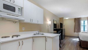 Cocina compacta con microondas, estufa y lavamanos. Cuenta con un pequeño comedor con mesa y sillas.