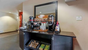 Una estación de café autoservicio con varias máquinas de café, un espejo y una variedad de bocadillos.