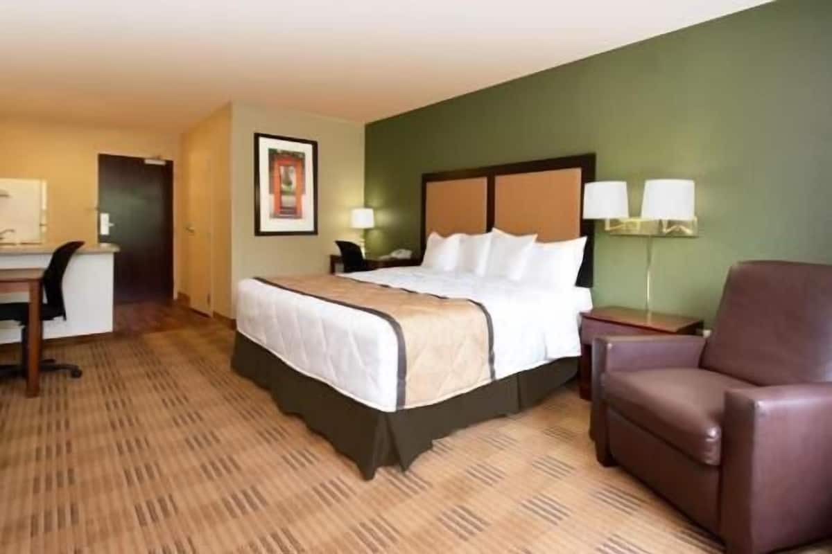 Una habitación de hotel con una cama, un escritorio, una silla y una lámpara.