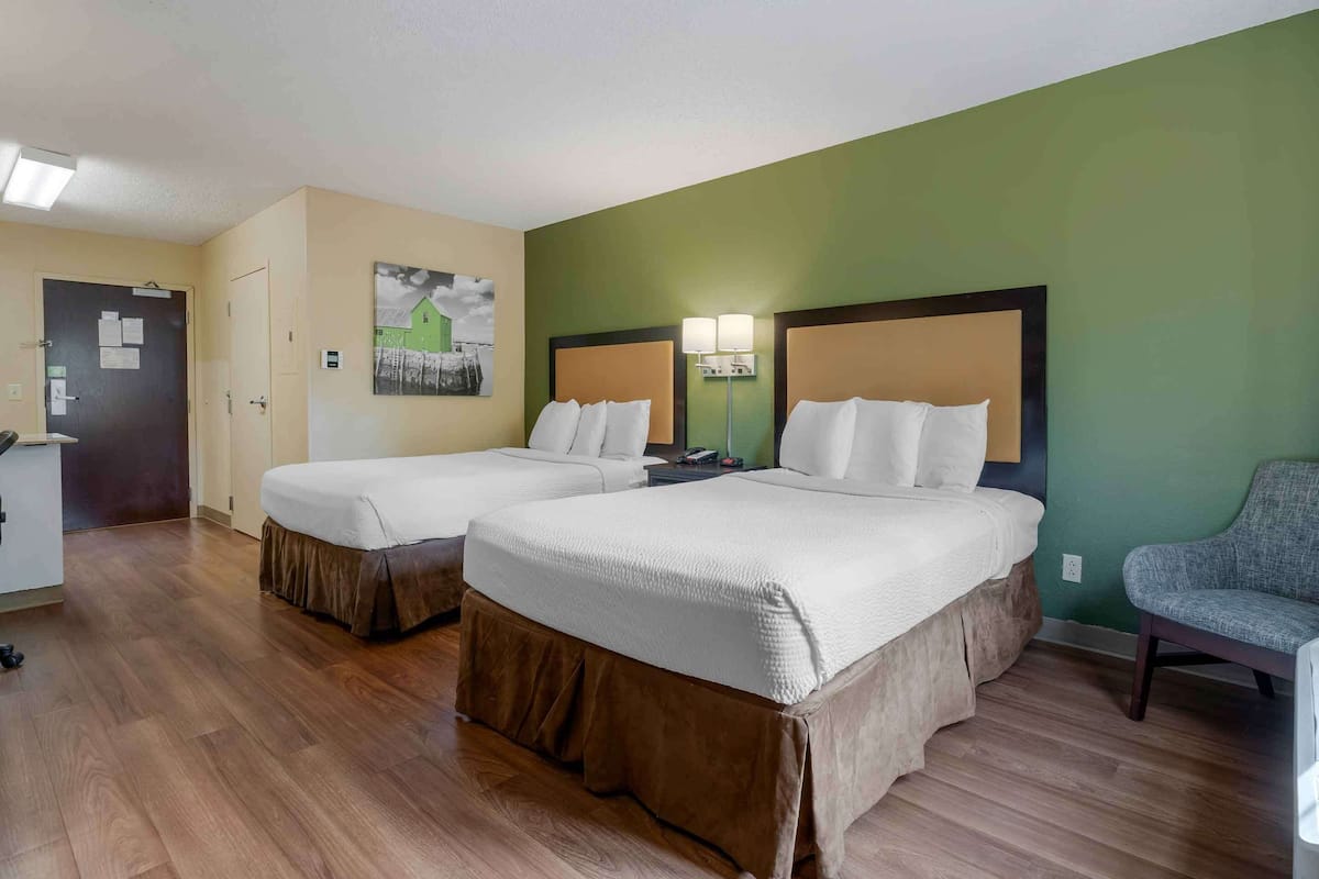 Habitación de hotel con dos camas, un escritorio y una silla.