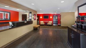 Eine Hotelhalle mit einer Rezeption, einer Sitzecke und Kaffeeautomaten.