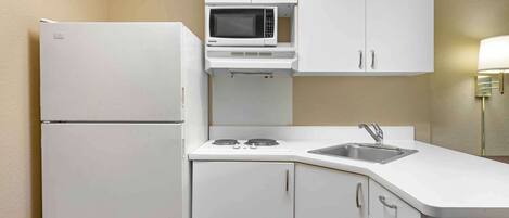 Una cocina compacta con microondas integrado, estufa y lavamanos.
