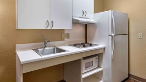 A compact kitchen with white cabinets, a sink, a stove, a microwave, and a refrigerator. - Extended Stay America Suites Chicago Elmhurst O'Hare (Elmhurst)