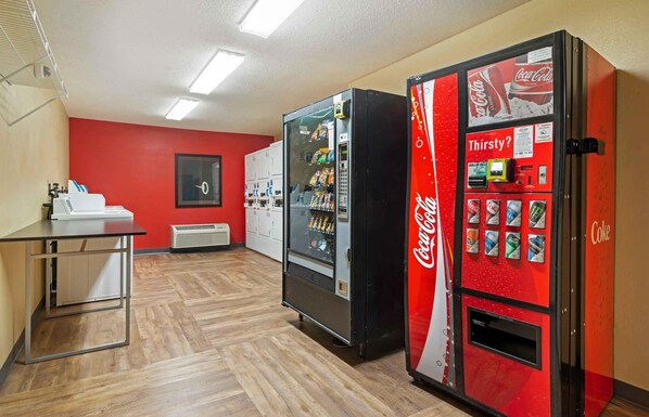 A room with a vending machine, a table, and a wall-mounted air conditioning unit.