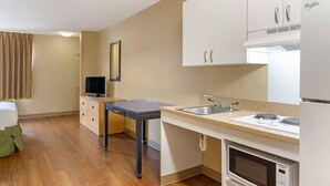 A compact kitchen with a sink, stove, microwave, and a small table with a television. - Extended Stay America Select Suites - Atlanta - Duluth (Duluth)