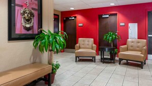 A reception area with a bench, two leather chairs, a potted plant, and a framed artwork on the wall. - Extended Stay America Select Suites - Jacksonville - Lenoir Avenue East (Jacksonville)