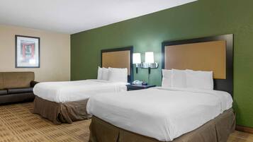 A hotel room with two beds, a sofa, and a framed picture on the wall.