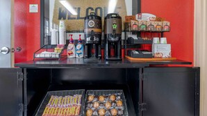 Una estación de café con dos máquinas de café, un letrero que dice “BIENVENIDOS” y diferentes cápsulas y recipientes de café.