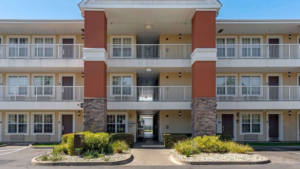 Un hotel America para estancias prolongadas, de varios pisos, con entrada central, balcones y estacionamiento.