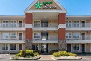 A multi-story extended stay America hotel with a central entrance, balconies, and a parking lot.