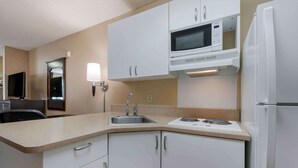 Cocina compacta con armarios blancos, un microondas, un lavabo y una estufa.