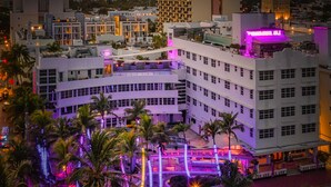 Ein Hotel mit Innenhof, Palmen und einem Neon-Schild.