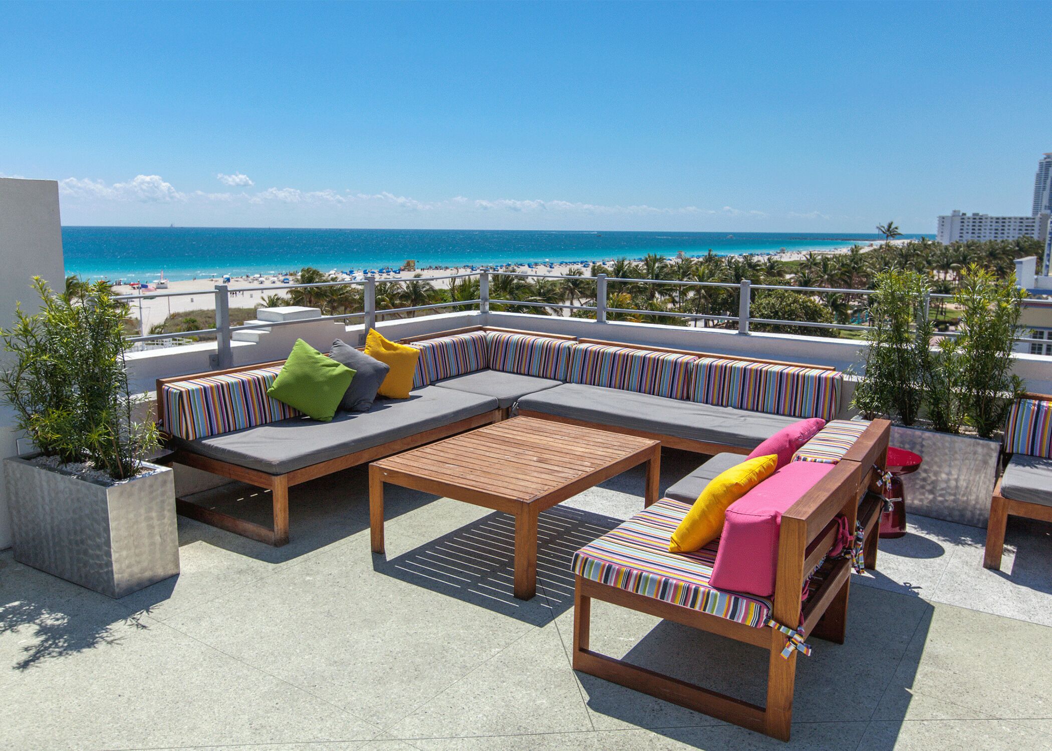 A rooftop terrace with a view of the beach and ocean.
