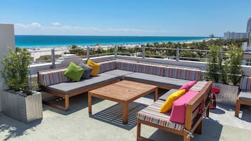 A rooftop terrace with a view of the beach and ocean.