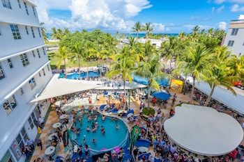 A rooftop bar with a long counter, seating area, and a patterned wall behind the bar. at Clevelander Hotel – Adults Only