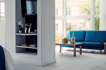 A modern hotel lobby with a check-in desk, orange sofas, a coffee table, and large windows with curtains. at Clevelander Hotel – Adults Only