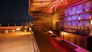 Eine Dachterrasse mit einer langen Theke, einer Sitzgelegenheit und einer gemusterten Wand im Hintergrund.