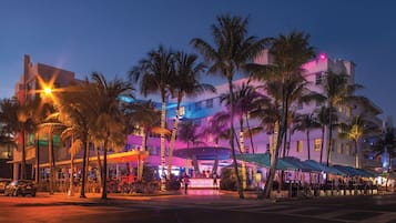 A hotel with multiple floors, outdoor seating areas, and palm trees.