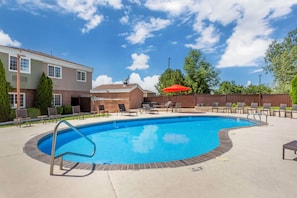 A swimming pool with a metal ladder, surrounded by lounge chairs and a red umbrella. - Best Western Mountain View Inn (Springville)