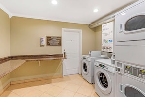 A hotel laundry room with a sign indicating guest laundry use, a coin slot for payment, and a wall-mounted soap and bleach sign. - Best Western Mountain View Inn (Springville)