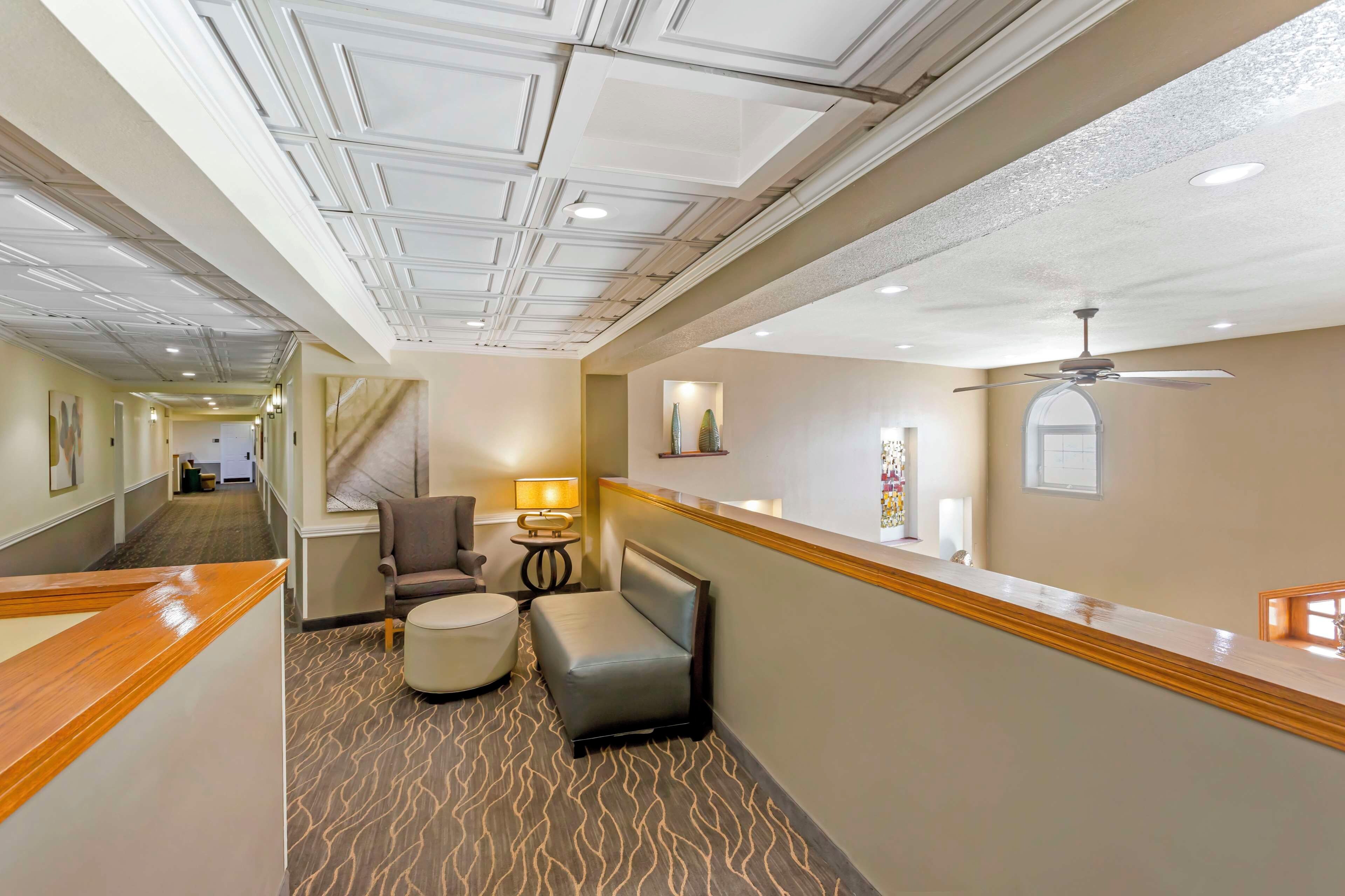 A hotel corridor with a reception desk, seating area, and a ceiling fan.