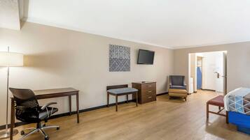 Habitación de hotel con escritorio, silla, cama y televisor en la pared.
