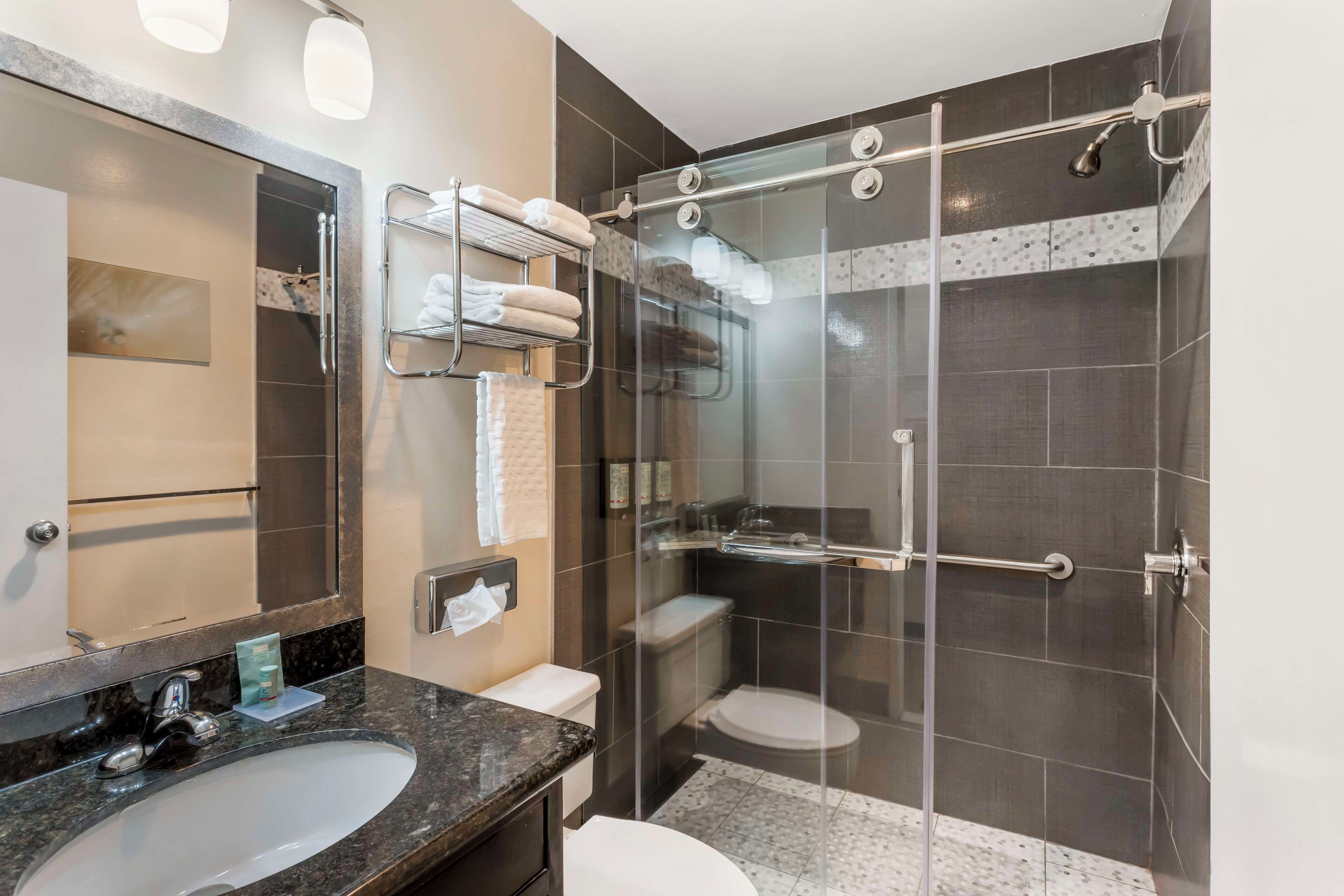 Un baño moderno con ducha de vidrio, lavamanos de mármol y un perchero para toallas.