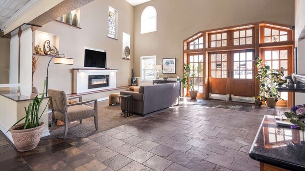 A spacious living area with a fireplace, comfortable seating, and a large window with a view. - Best Western Mountain View Inn (Springville)