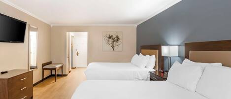 A hotel room with two beds, a desk, a chair, a flat-screen TV, and a painting on the wall.