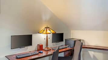 A small, private office with a desk, two monitors, a keyboard, a mouse, a lamp, and a printer.
