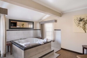 A modern bathroom with a large bathtub, a vanity with a mirror, and a small table.