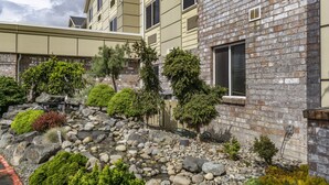 A building with a brick facade and a landscaped garden with rocks and shrubs.