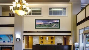 A hotel reception area with a fireplace, a chandelier, a large TV screen, and a reception desk.