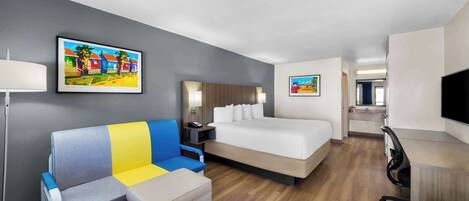 A hotel room with a bed, a sofa, a desk, and a TV.