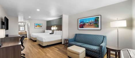 A hotel room with a bed, a sofa, a desk, and a lamp.
